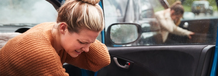 Chiropractic Brentwood CA Auto Injury A young woman leaving her vehicle after an auto accident, holding her neck in pain