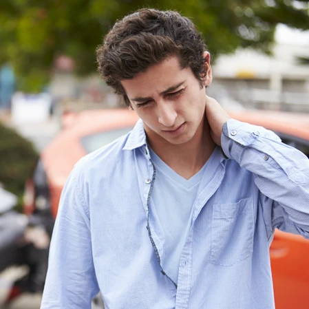 A young man holding his neck in pain after a car accident