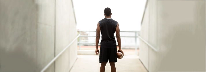 Chiropractic Concord CA Sports Injury A football player stands in an empty stadium with a football in hand, staring out at the field.