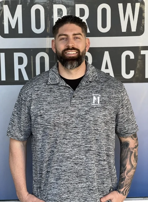 Dr. Alexander Morrow standing in front of a Morrow Chiropractic sign
